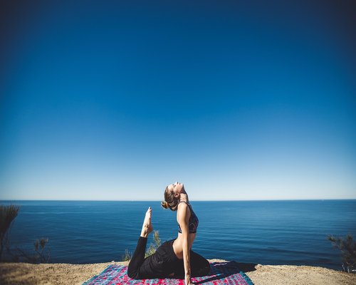 Woman doing yoga stretching outdoors in sunlight